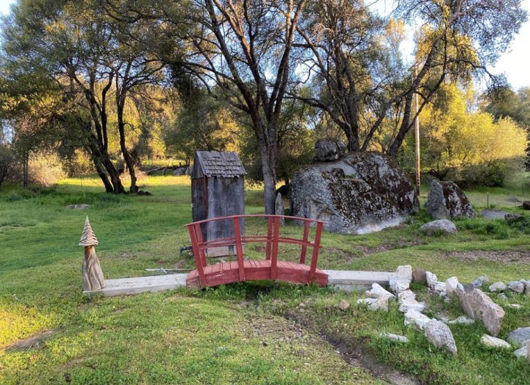 Small red bridge among oak trees and granite boulders