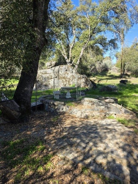 Quiet garden path with granite, oak trees and a small arbor
