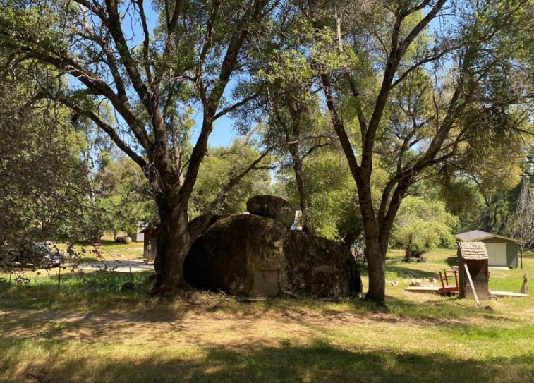 Large granite boulder beneath oak trees on the property