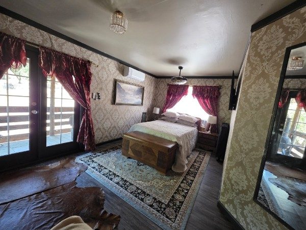 Wide view of the queen bedroom with balcony doors and vintage furnishings